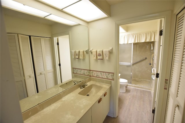 bathroom with a shower, toilet, vanity, and hardwood / wood-style flooring