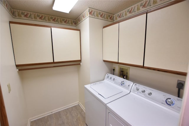 laundry area with washing machine and clothes dryer, light hardwood / wood-style flooring, cabinets, and a textured ceiling