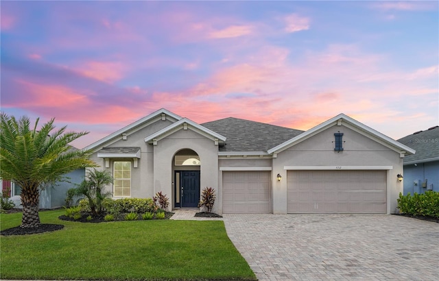 ranch-style home featuring a garage and a lawn