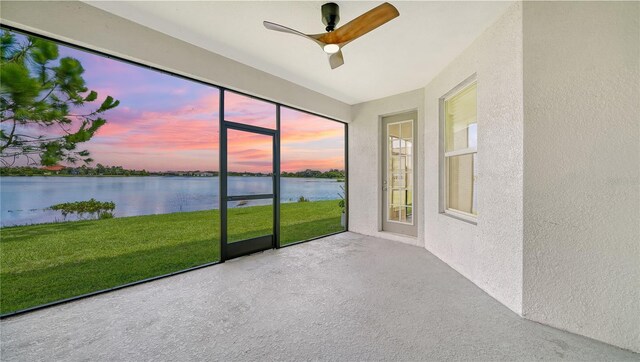 unfurnished sunroom with a water view and ceiling fan