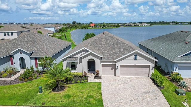 view of front of house with a front yard, a water view, and a garage