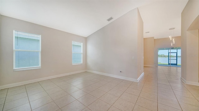 empty room with light tile patterned floors and vaulted ceiling