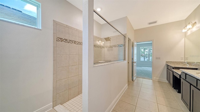 bathroom with tile patterned floors, tiled shower, and vanity