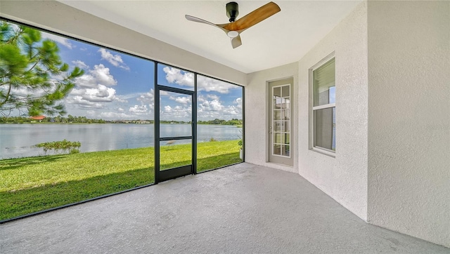 unfurnished sunroom featuring a water view and ceiling fan