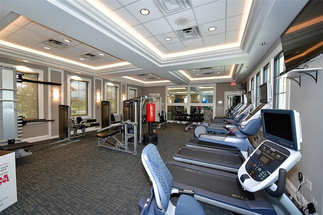 exercise room featuring crown molding, a raised ceiling, and carpet floors