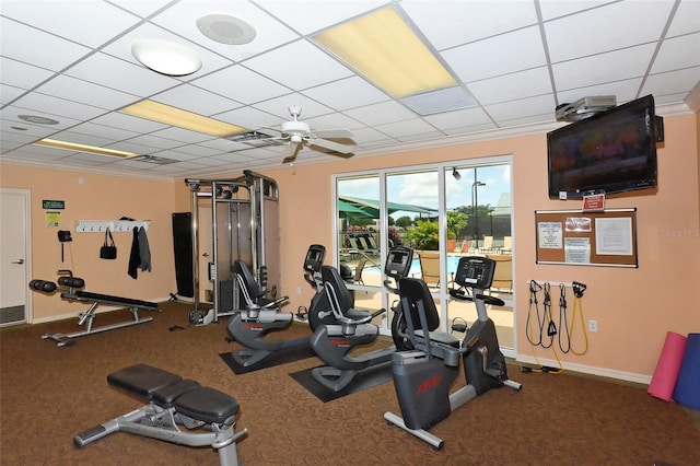 exercise room with ceiling fan, a paneled ceiling, and ornamental molding