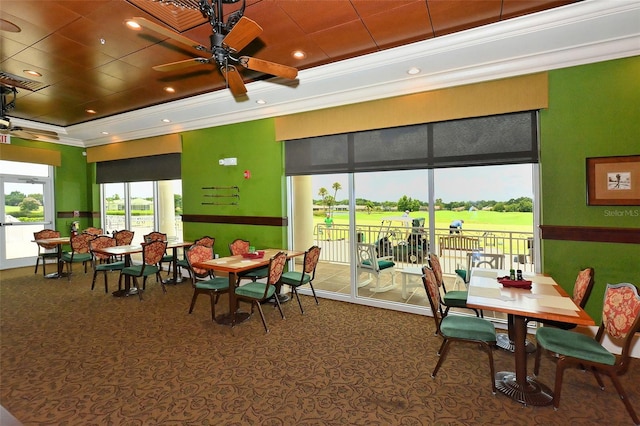 dining space with ceiling fan, a raised ceiling, crown molding, and carpet