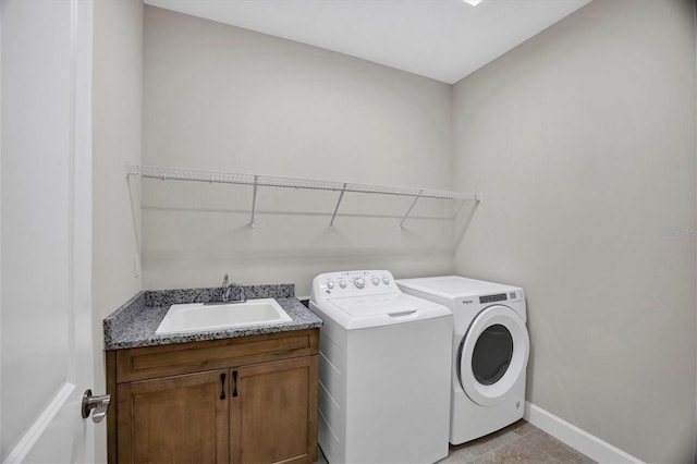 laundry room featuring washer and clothes dryer, sink, light tile patterned floors, and cabinets