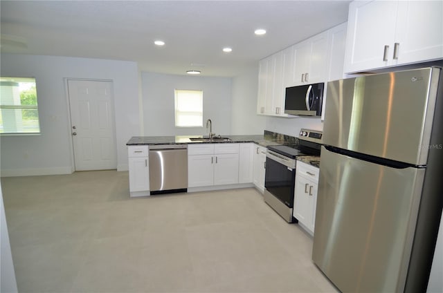 kitchen with a wealth of natural light, dark stone countertops, white cabinetry, and appliances with stainless steel finishes