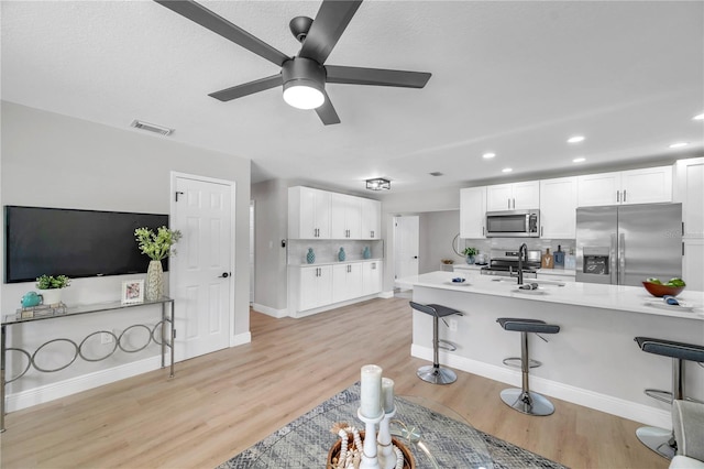 kitchen featuring white cabinets, a kitchen breakfast bar, stainless steel appliances, and light hardwood / wood-style flooring