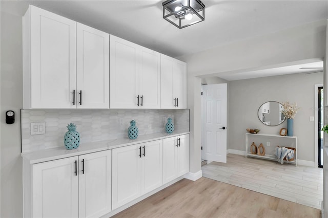 kitchen with light wood-type flooring, tasteful backsplash, and white cabinets