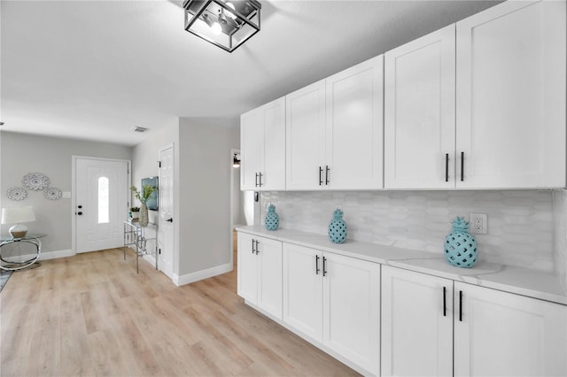 kitchen with light hardwood / wood-style flooring, backsplash, and white cabinets