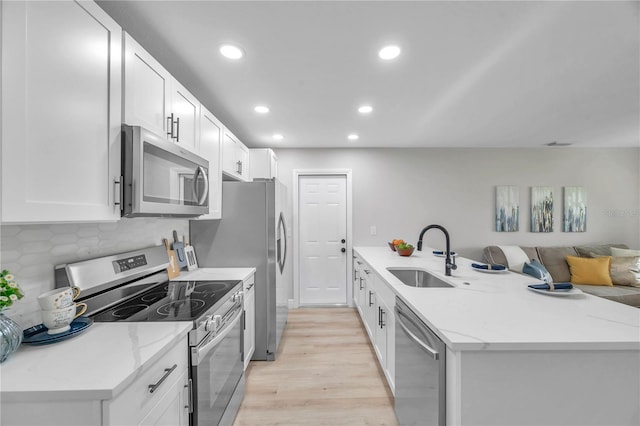 kitchen with light hardwood / wood-style flooring, appliances with stainless steel finishes, sink, white cabinetry, and light stone counters