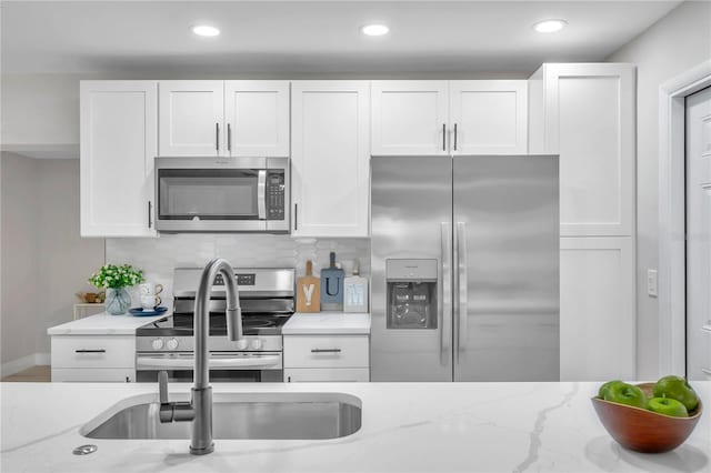 kitchen with white cabinets, appliances with stainless steel finishes, and light stone countertops