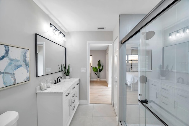 bathroom featuring vanity, toilet, an enclosed shower, and tile patterned floors