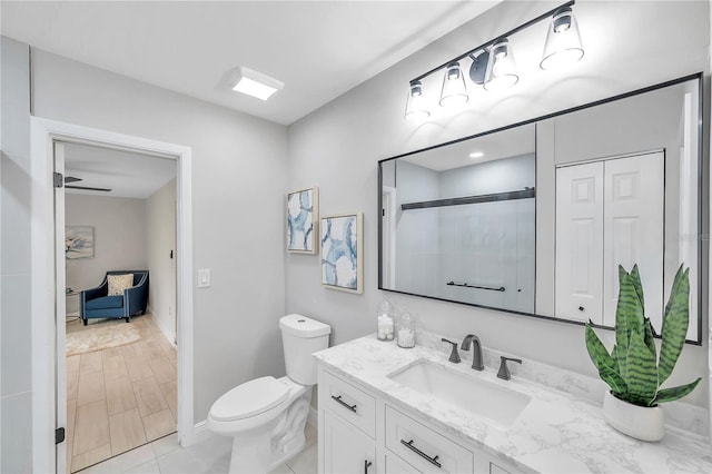 bathroom featuring vanity, a shower with shower door, wood-type flooring, toilet, and ceiling fan