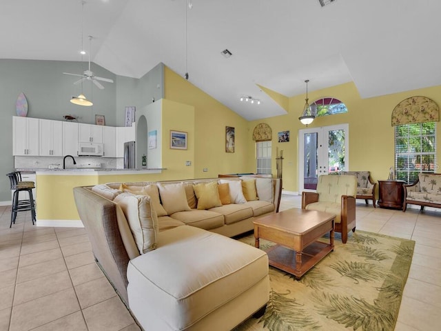 living area featuring light tile patterned floors, visible vents, high vaulted ceiling, and ceiling fan