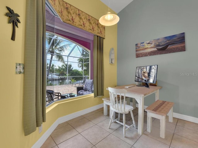 dining space with vaulted ceiling, light tile patterned flooring, and baseboards