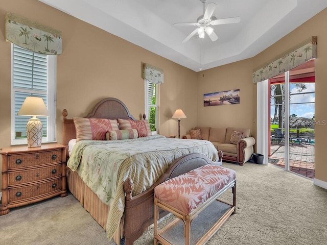 bedroom featuring light colored carpet, a raised ceiling, a ceiling fan, and access to outside