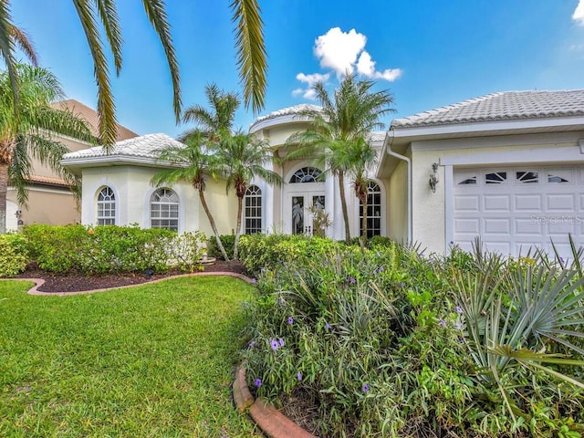 view of front of house featuring a front yard, an attached garage, stucco siding, french doors, and a tile roof