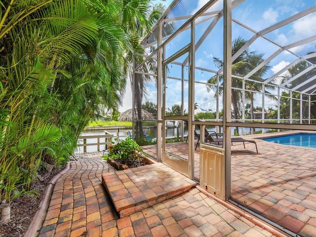 pool with a lanai, a water view, and a patio