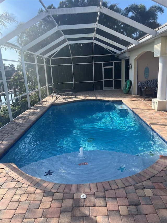 outdoor pool featuring glass enclosure and a patio