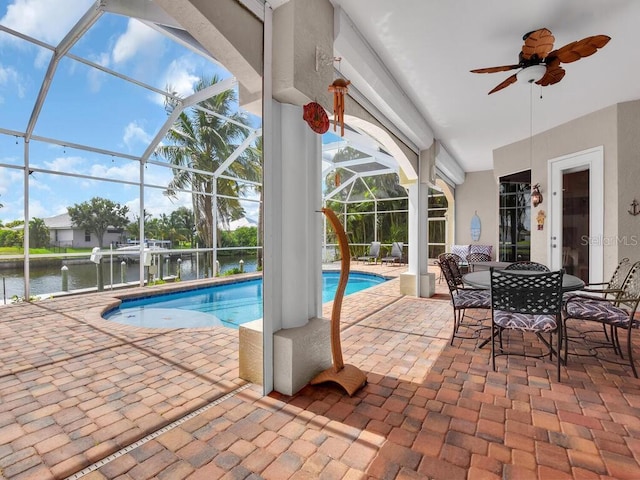 pool featuring a patio area, glass enclosure, a ceiling fan, and a water view