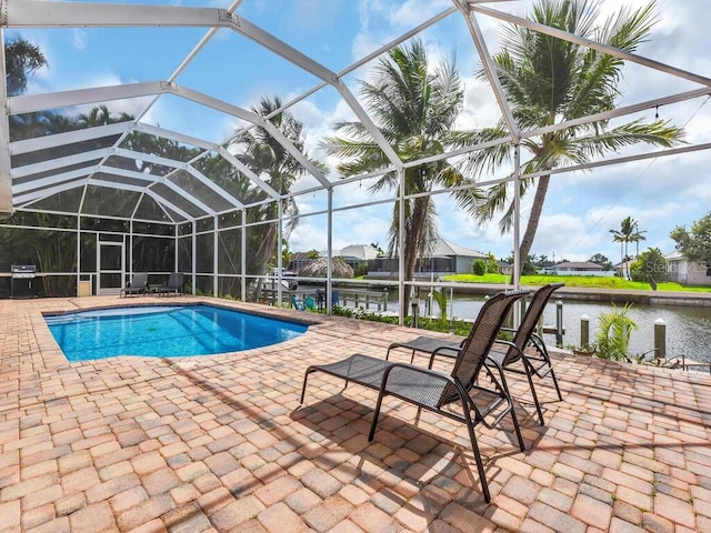 outdoor pool featuring a patio area, glass enclosure, a grill, and a water view