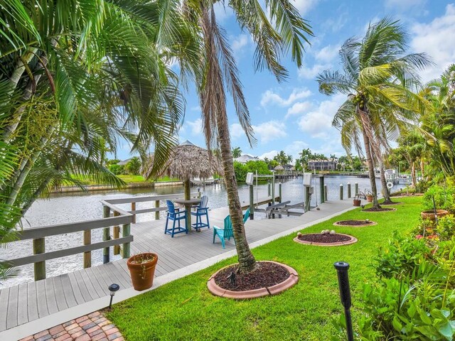 dock area with boat lift, a water view, and a lawn