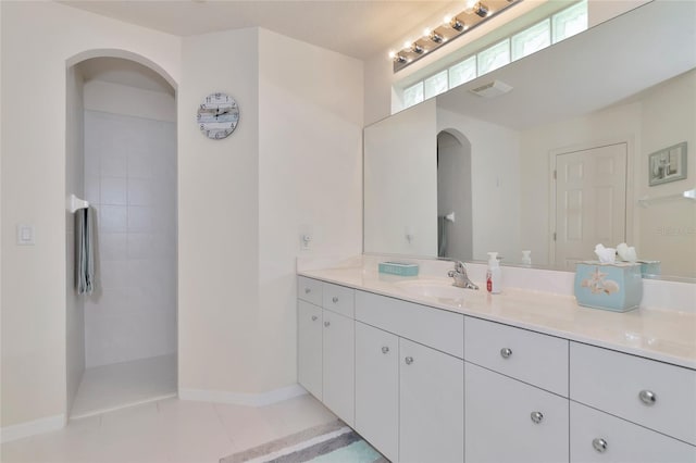 bathroom featuring a tile shower, vanity, and tile patterned flooring