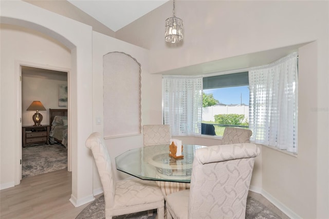 dining area featuring light hardwood / wood-style flooring, vaulted ceiling, and an inviting chandelier