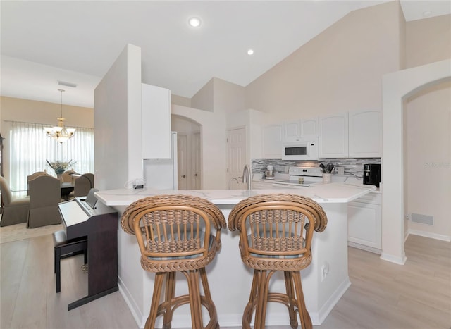 kitchen with white cabinets, light hardwood / wood-style flooring, a chandelier, and white appliances