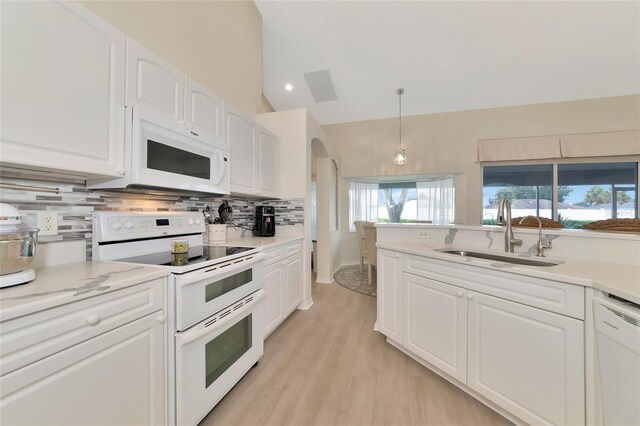 kitchen with vaulted ceiling, white cabinets, white appliances, pendant lighting, and sink