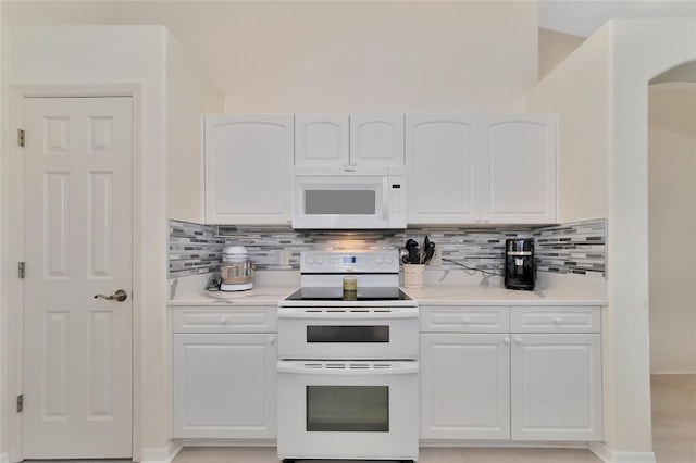 kitchen featuring decorative backsplash, white cabinets, and white appliances