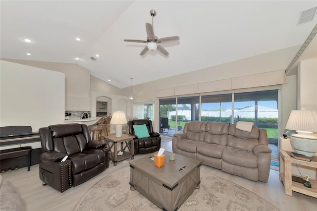 living room with light wood-type flooring, vaulted ceiling, ceiling fan, and a healthy amount of sunlight