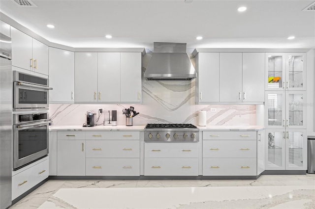 kitchen with wall chimney exhaust hood, recessed lighting, backsplash, stainless steel gas stovetop, and marble finish floor