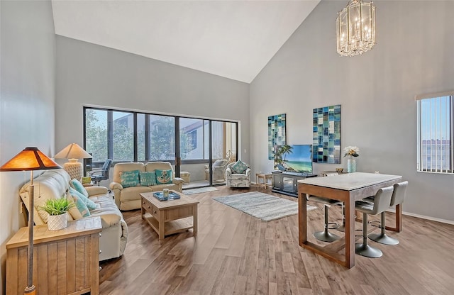 living room with high vaulted ceiling, plenty of natural light, hardwood / wood-style floors, and an inviting chandelier