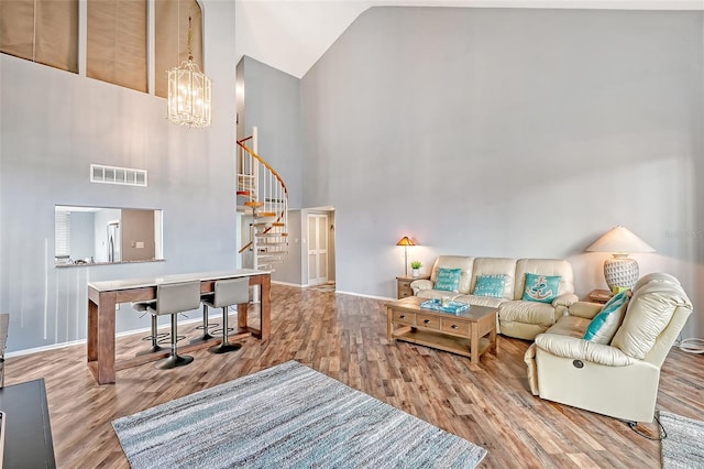 living room featuring hardwood / wood-style floors, high vaulted ceiling, and an inviting chandelier