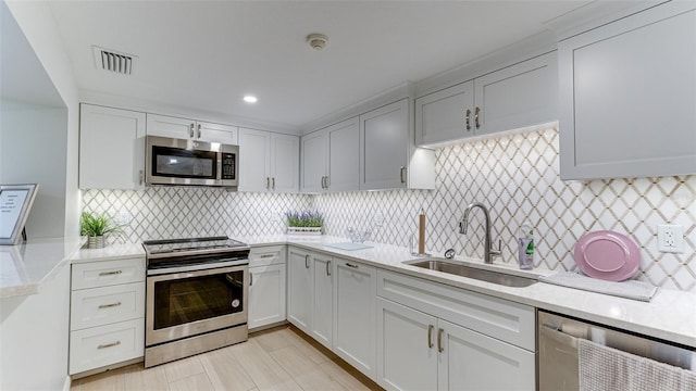 kitchen with sink, light stone countertops, appliances with stainless steel finishes, and decorative backsplash