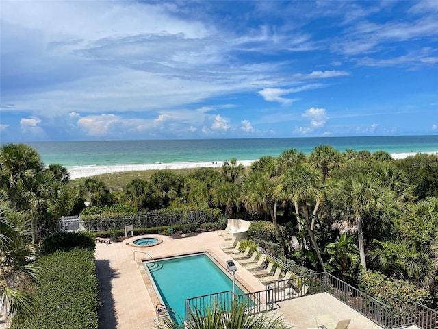 view of swimming pool featuring a view of the beach, a water view, and a patio