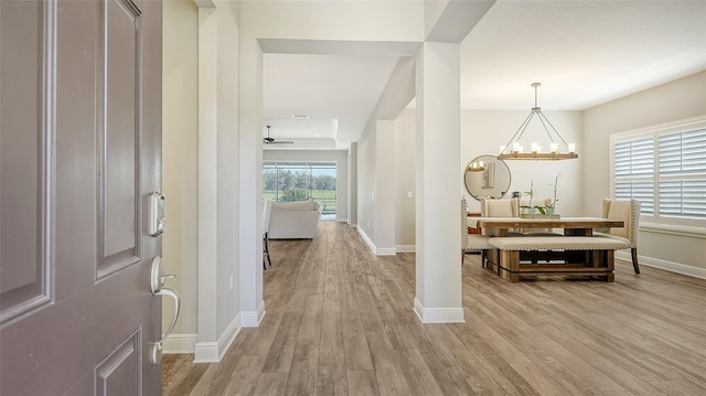 foyer entrance featuring light wood-type flooring and ceiling fan with notable chandelier