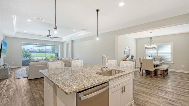 kitchen with dishwasher, hardwood / wood-style flooring, sink, ceiling fan with notable chandelier, and white cabinets