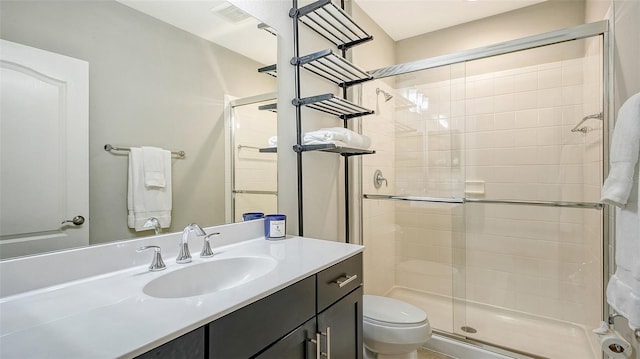 bathroom with vanity, a shower with shower door, and toilet