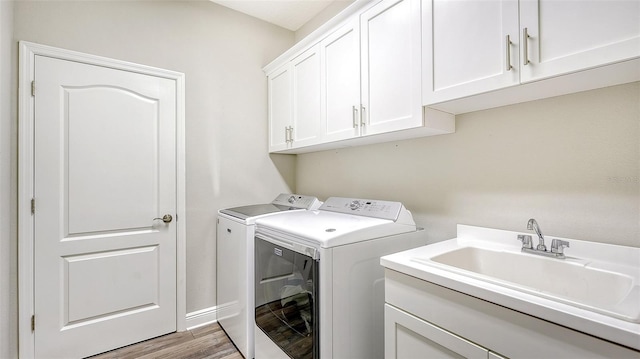 washroom with hardwood / wood-style flooring, washing machine and dryer, sink, and cabinets