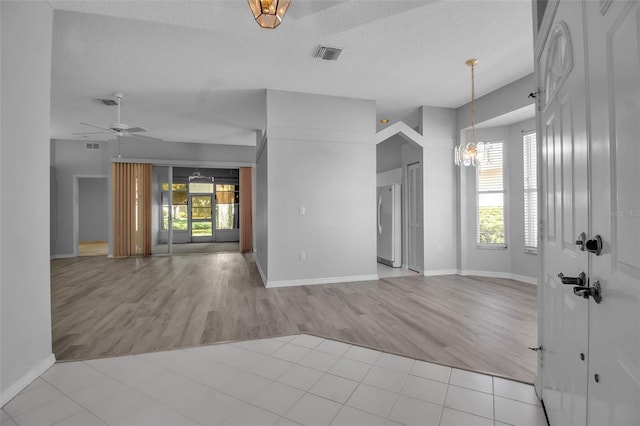 entryway featuring a textured ceiling, ceiling fan with notable chandelier, light hardwood / wood-style flooring, and a wealth of natural light