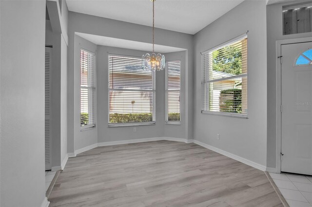 unfurnished dining area featuring light wood-type flooring and a chandelier