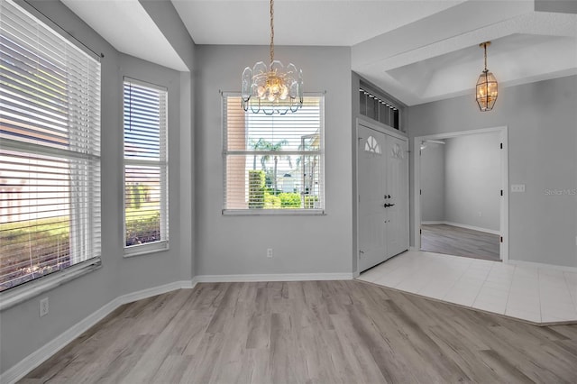 entryway with light hardwood / wood-style flooring, plenty of natural light, and a chandelier