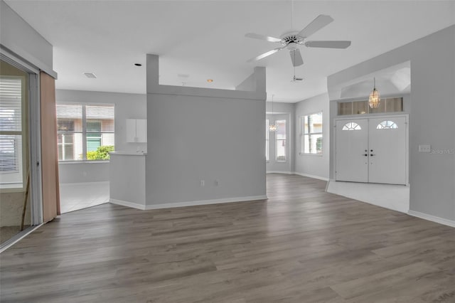 unfurnished living room with ceiling fan with notable chandelier and hardwood / wood-style floors