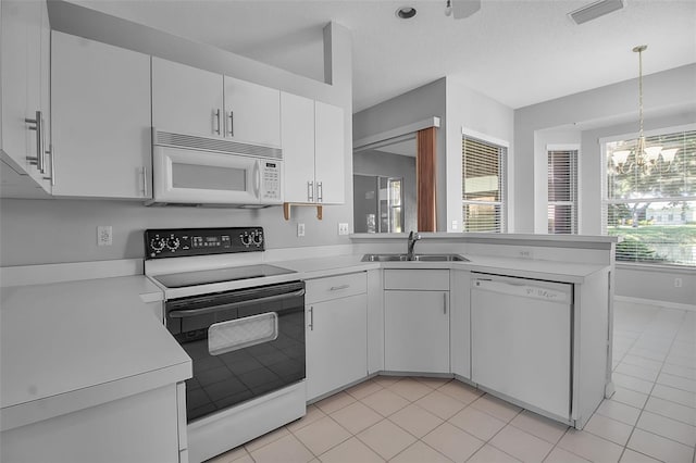 kitchen featuring a chandelier, sink, white cabinets, kitchen peninsula, and white appliances