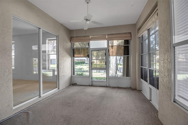 unfurnished sunroom featuring ceiling fan and plenty of natural light